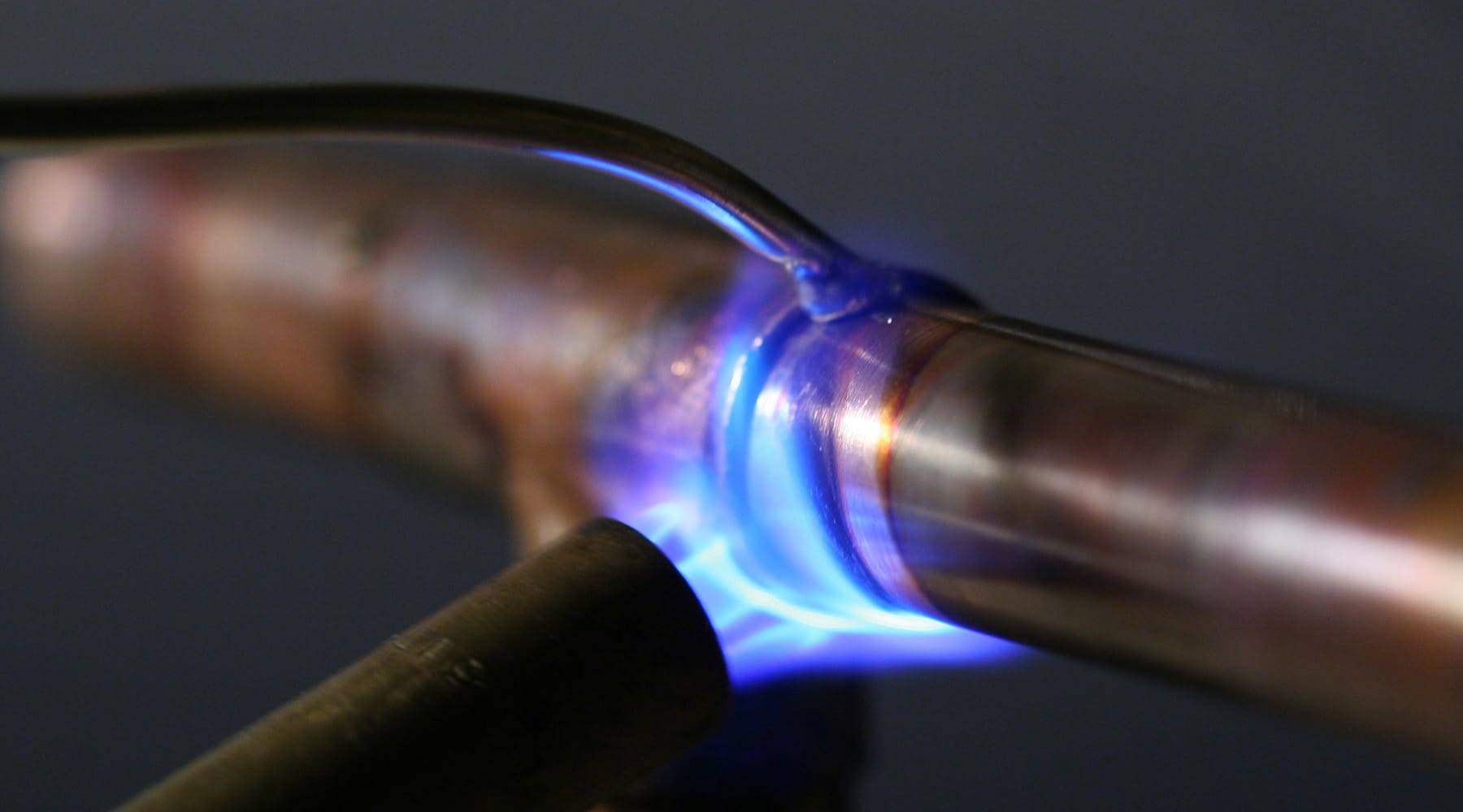 A close-up of a plumber using a propane torch to solder and sweat a copper pipe joint